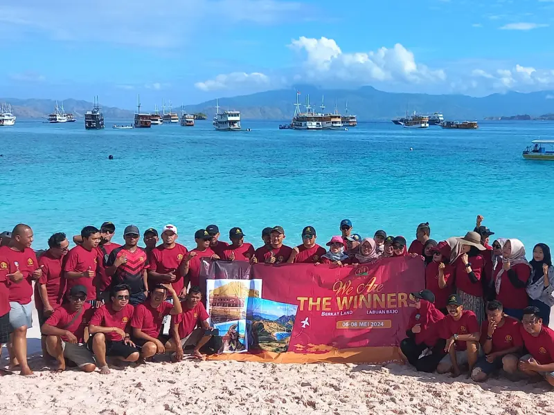 Rombongan corporate gathering PT The Winner Berkat Land Surabaya membentangkan banner di Pantai Pink Labuan Bajo.